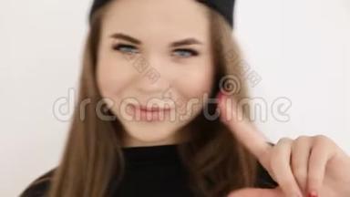 一个穿着黑色嘻哈服装，戴着帽子的十几岁女孩在白色的墙壁上跳舞-特写、手持射击、小深度。
